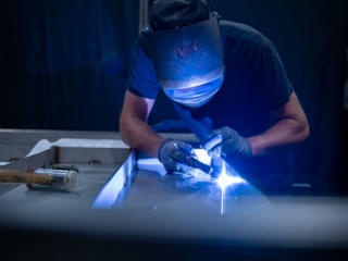 Image d'un soudeur dans un atelier, en train de construire des équipements métalliques.